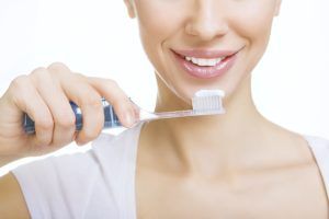 woman holding a toothbrush in front of her mouth with whitening toothpaste
